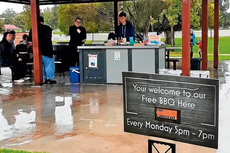 Rain, hail or shine, dedicated community member and mother Julie Birrer serves hot sausages and chicken burgers to the local community at Marie Bashir Park. Photo: Supplied